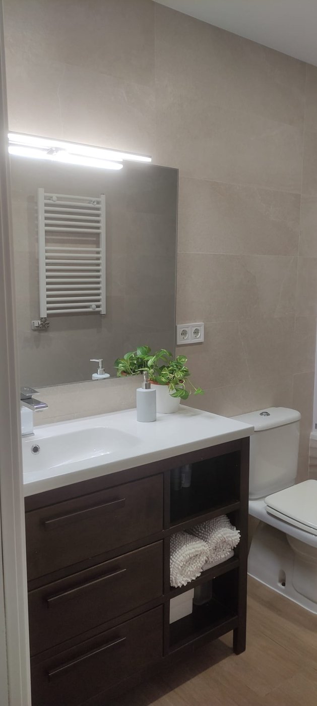 Baño reformado por Reformas CC García: mueble en tono nogal con radiador toallero