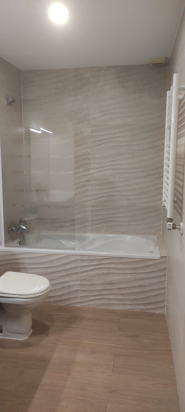 Baño reformado por Reformas CC García: bañera con alicatado ondulado